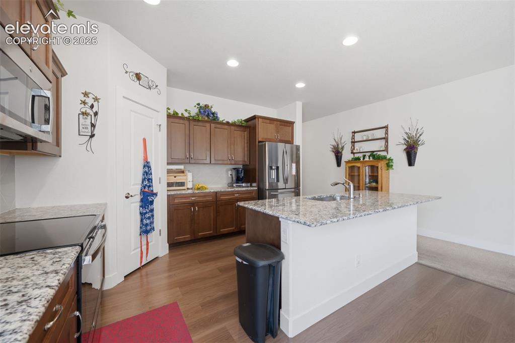Image 5 of 25: Kitchen featuring a central island with an undermount sink and extended cou