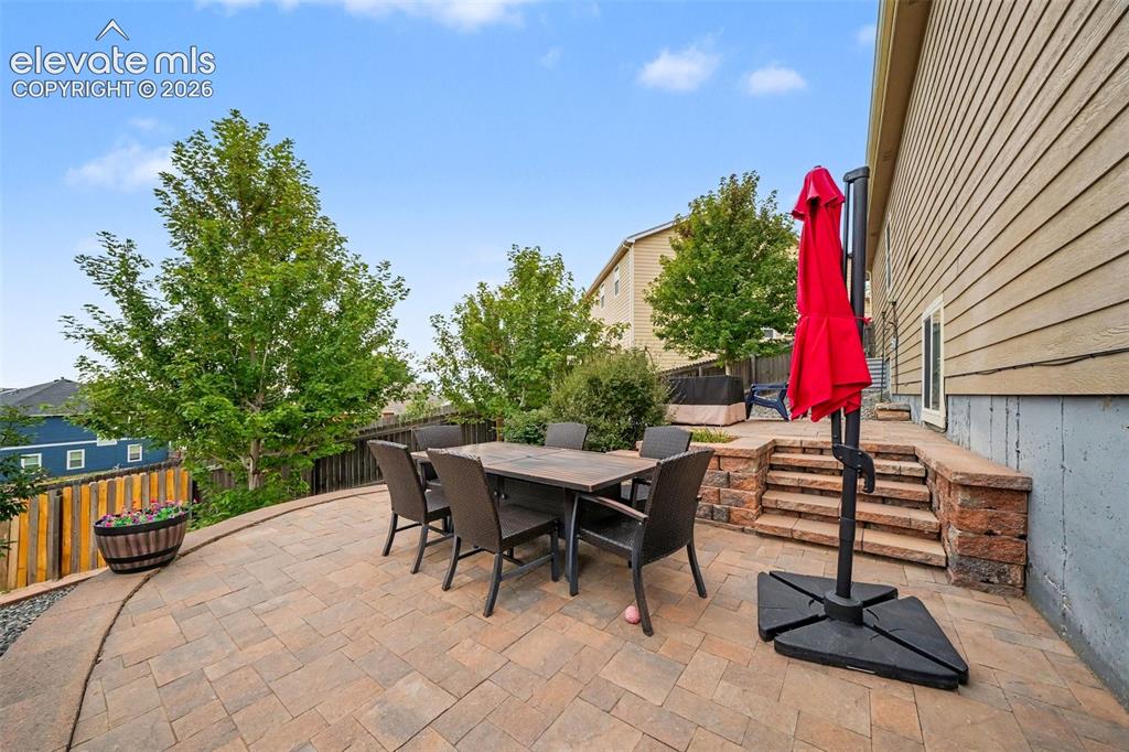 Image 18 of 21: Spacious paver patio with a terraced stone retaining wall