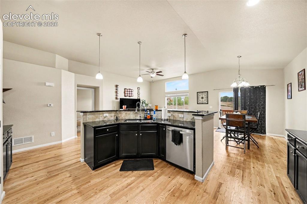 Image 4 of 21: Open-concept living space featuring wood-finish flooring and vaulted ceilin