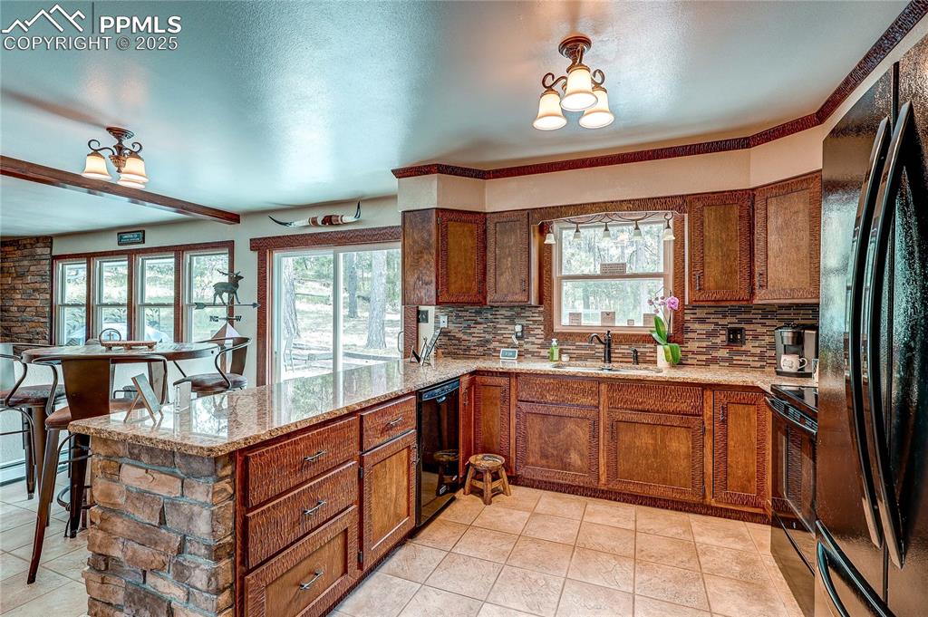 Image 14 of 49: Kitchen featuring a peninsula, black appliances, backsplash, and plenty of