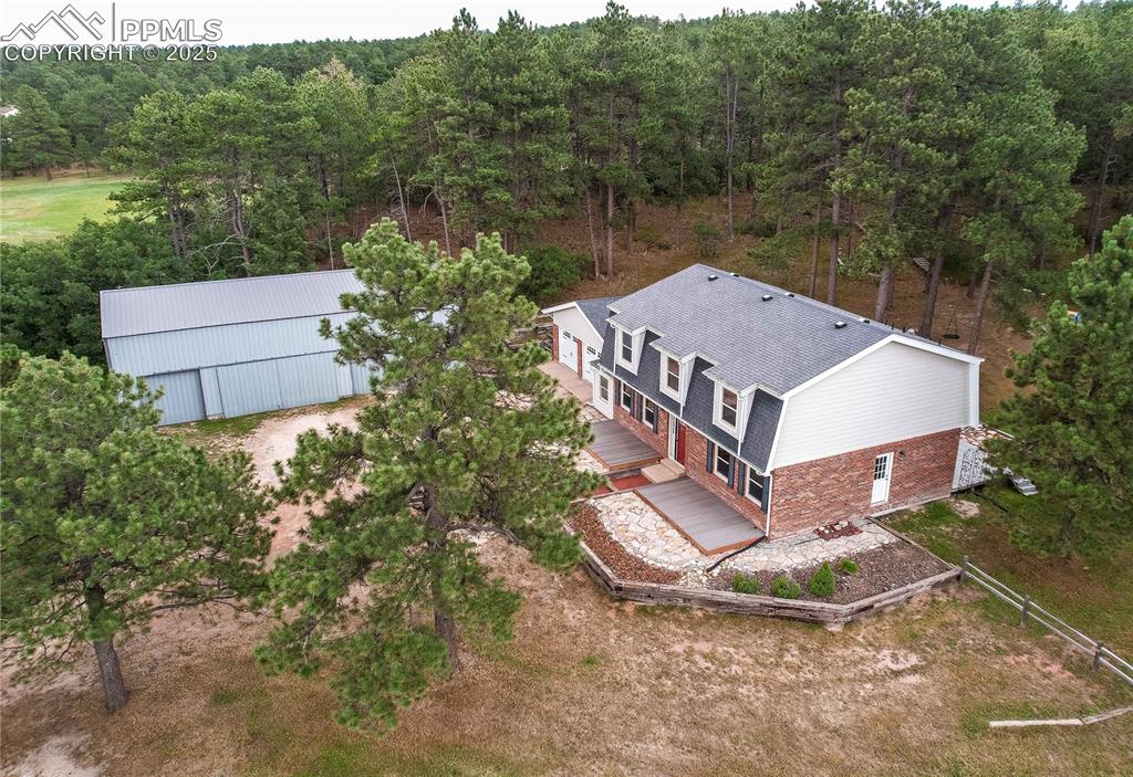 Image 2 of 49: Aerial view of property and surrounding area with a heavily wooded area
