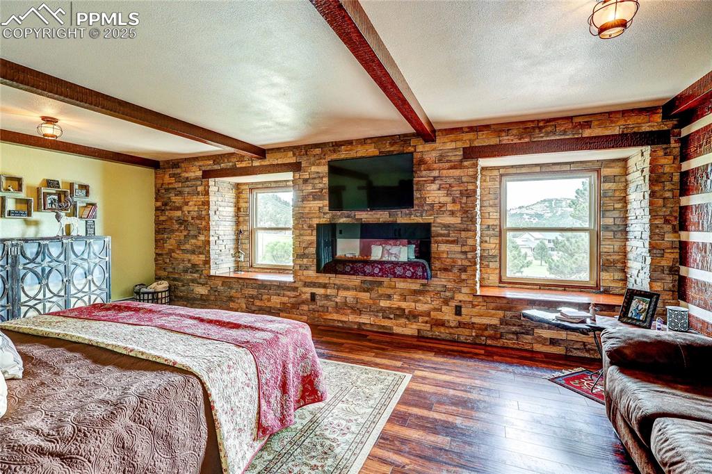 Image 20 of 49: Bedroom with beam ceiling, hardwood / wood-style floors, and a textured cei