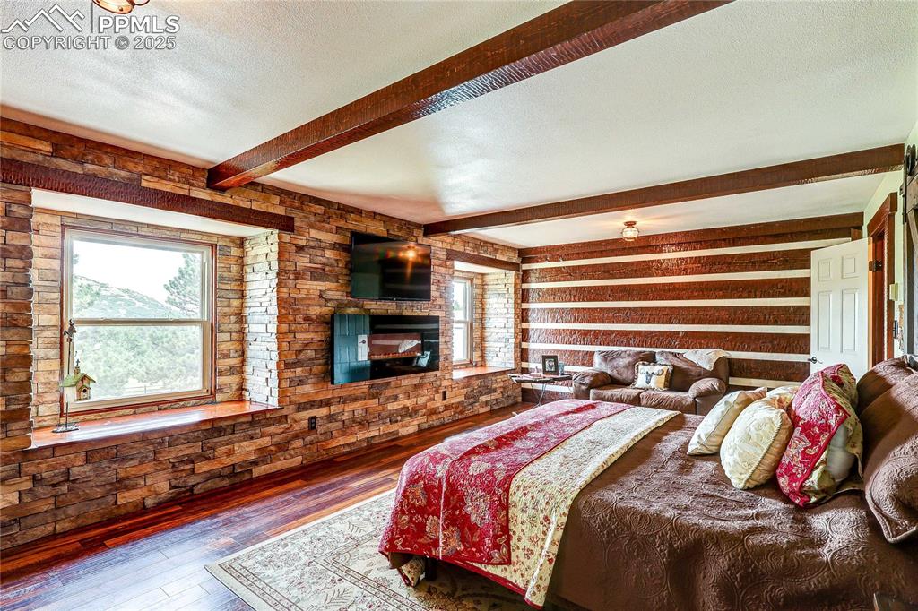 Image 22 of 49: Bedroom with multiple windows, beamed ceiling, hardwood / wood-style floori