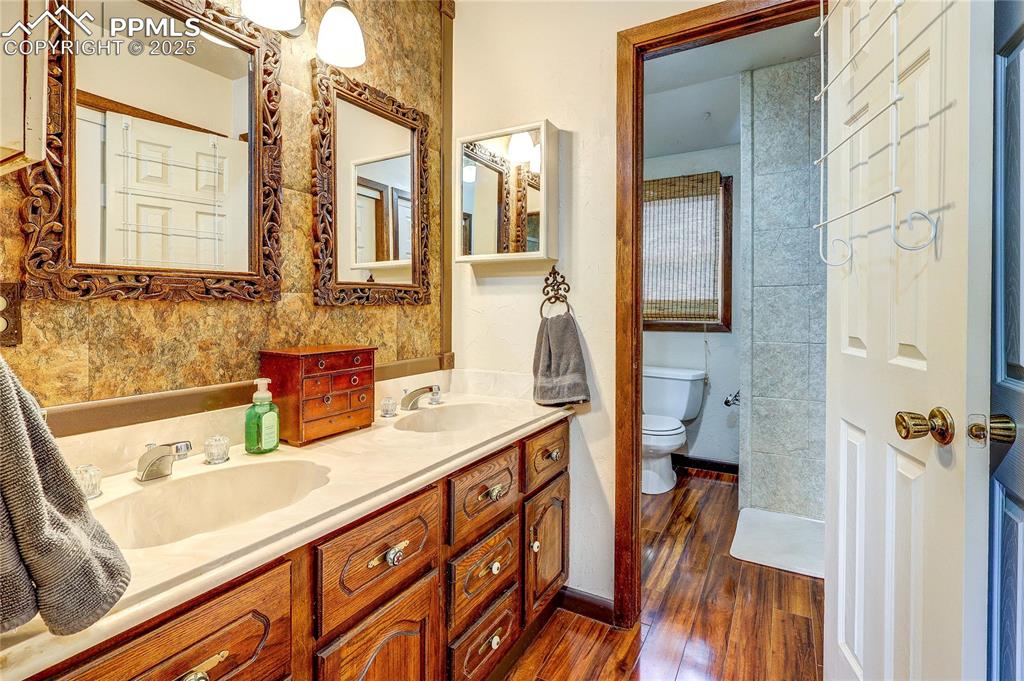 Image 24 of 49: Full bathroom with wood finished floors and double vanity