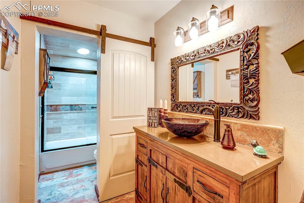 Image 29 of 49: Full upstairs bathroom featuring vanity and bath / shower combo with glass