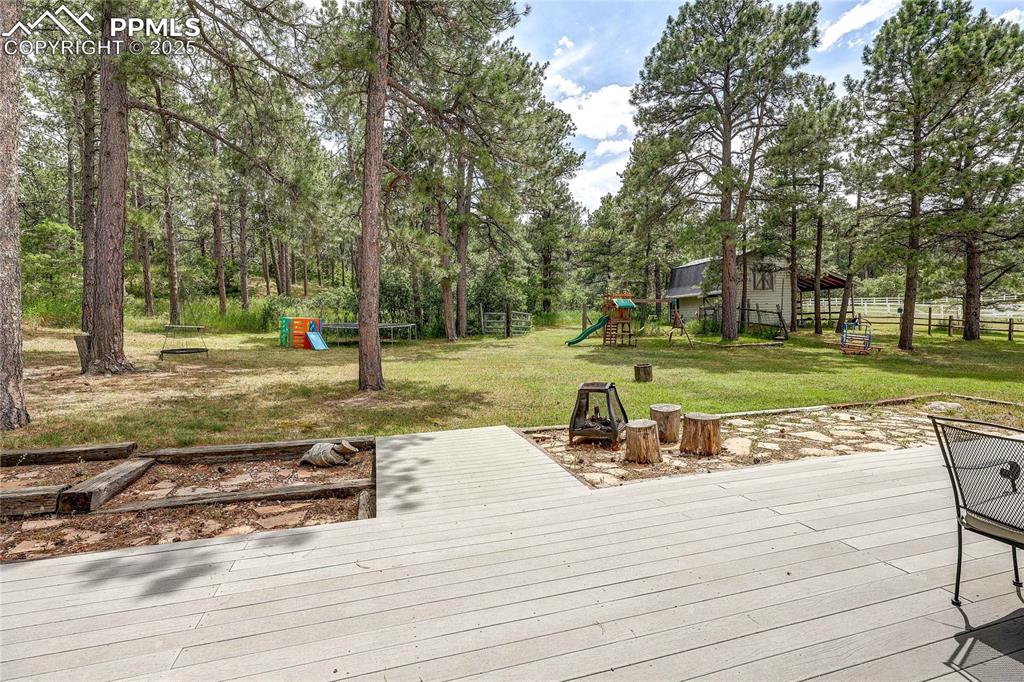 Image 37 of 49: Wooden terrace featuring a playground
