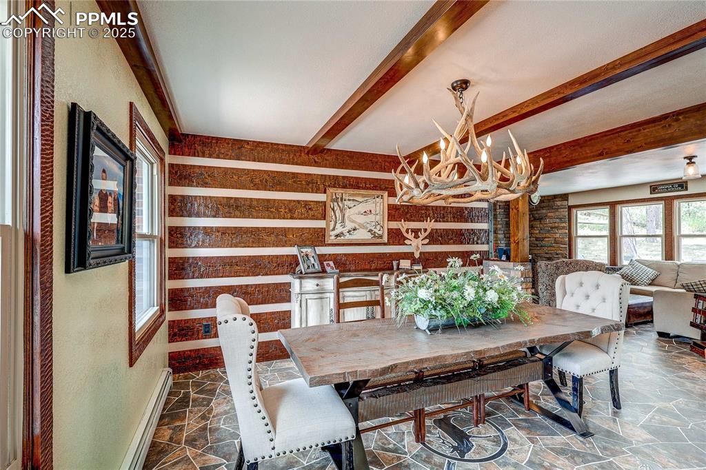 Image 6 of 49: Dining area with a chandelier, stone flooring, baseboard heating, and beame