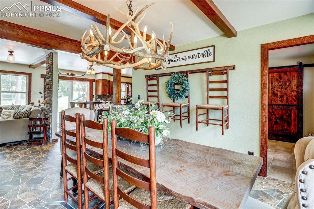 Image 7 of 49: Dining room featuring beamed ceiling and stone finish flooring