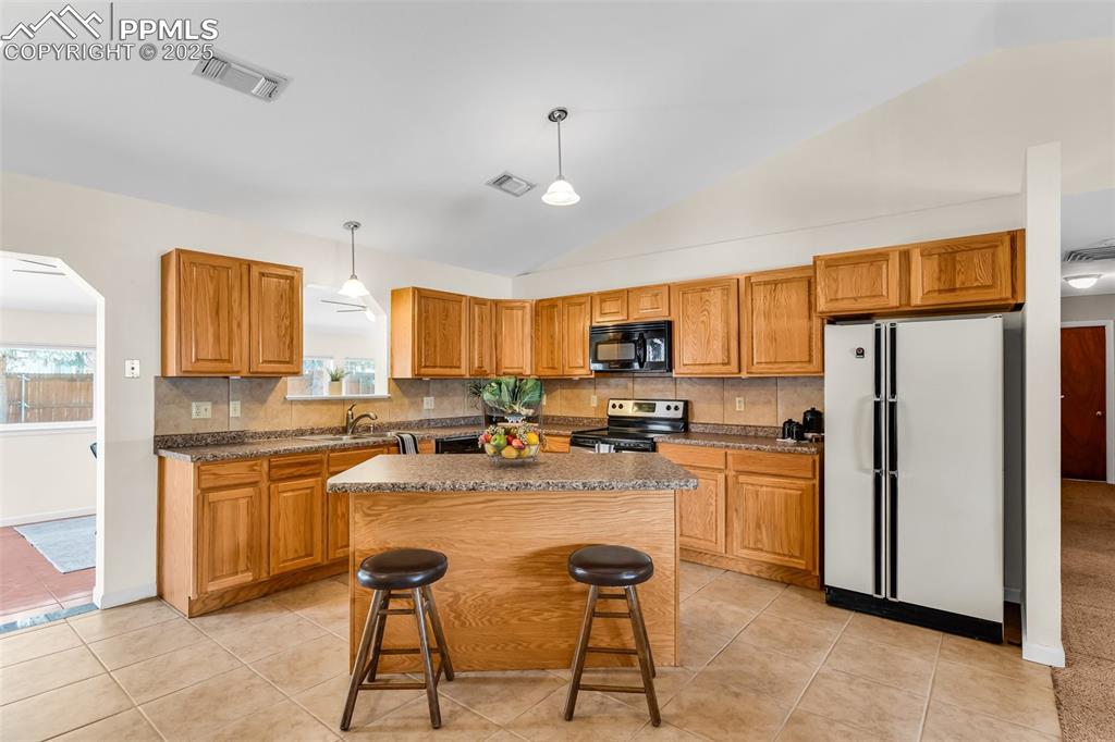 Image 11 of 42: Kitchen with black microwave, freestanding refrigerator, stainless steel el