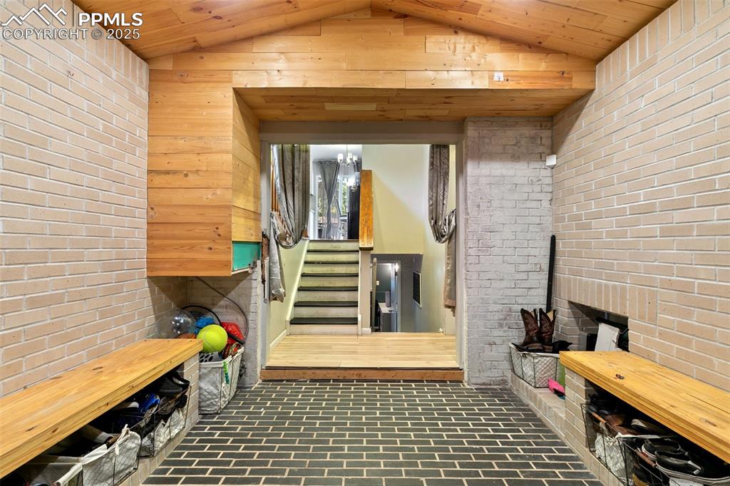 Image 6 of 38: Mudroom featuring brick wall, brick floors, vaulted ceiling, wood ceiling,
