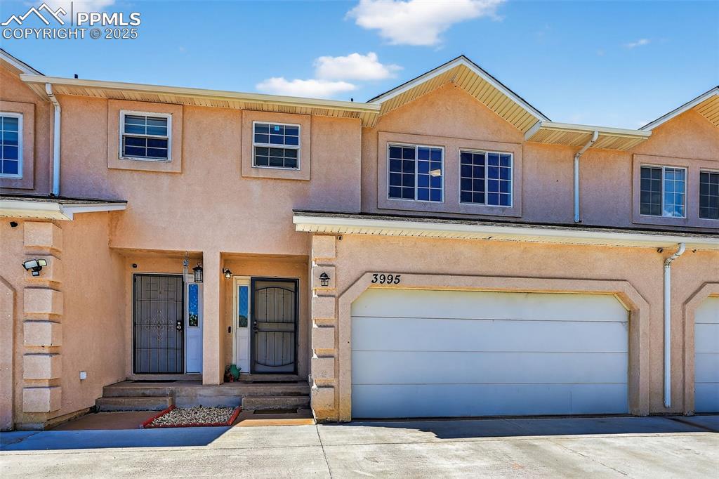 Caption: Townhome / multi-family property featuring stucco siding, an attached garage, and driveway
