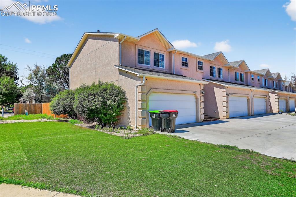 Image 2 of 26: View of front of condominiums - with driveway, stucco siding, and a garages