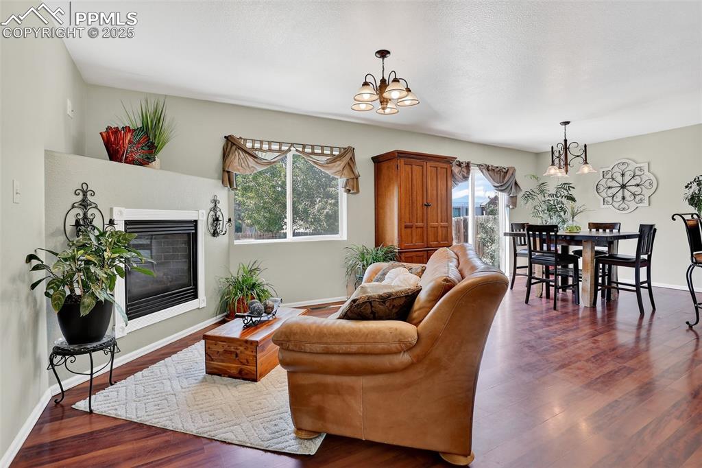 Image 4 of 26: Living room with a chandelier, dark wood finished floors, and a gas firepla