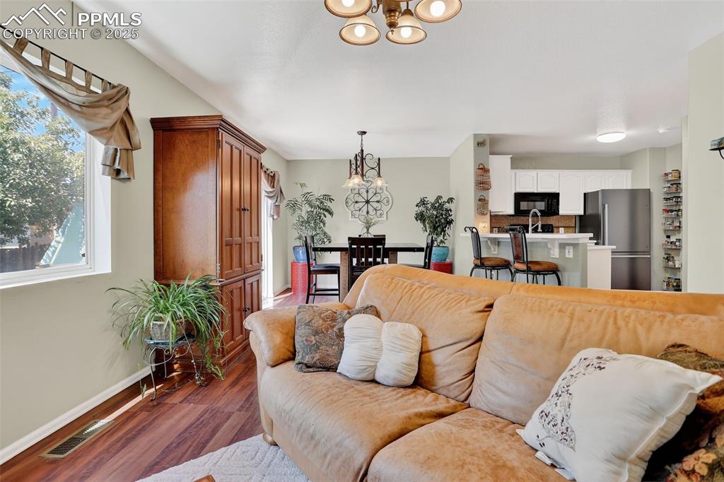 Image 6 of 26: Living area with a chandelier and wood finished floors
