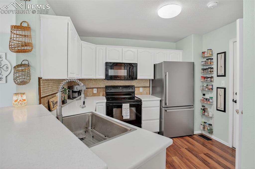 Image 8 of 26: Kitchen with appliances, light wood-style floors, decorative backsplash, wh
