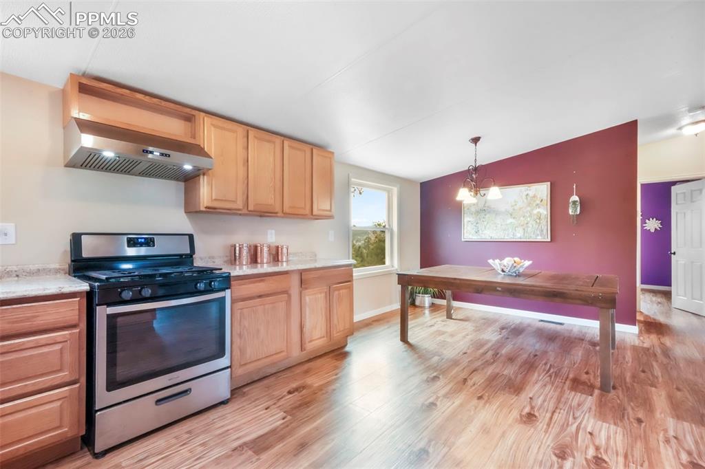 Image 10 of 50: Kitchen featuring vaulted ceiling, pendant lighting, light countertops, app