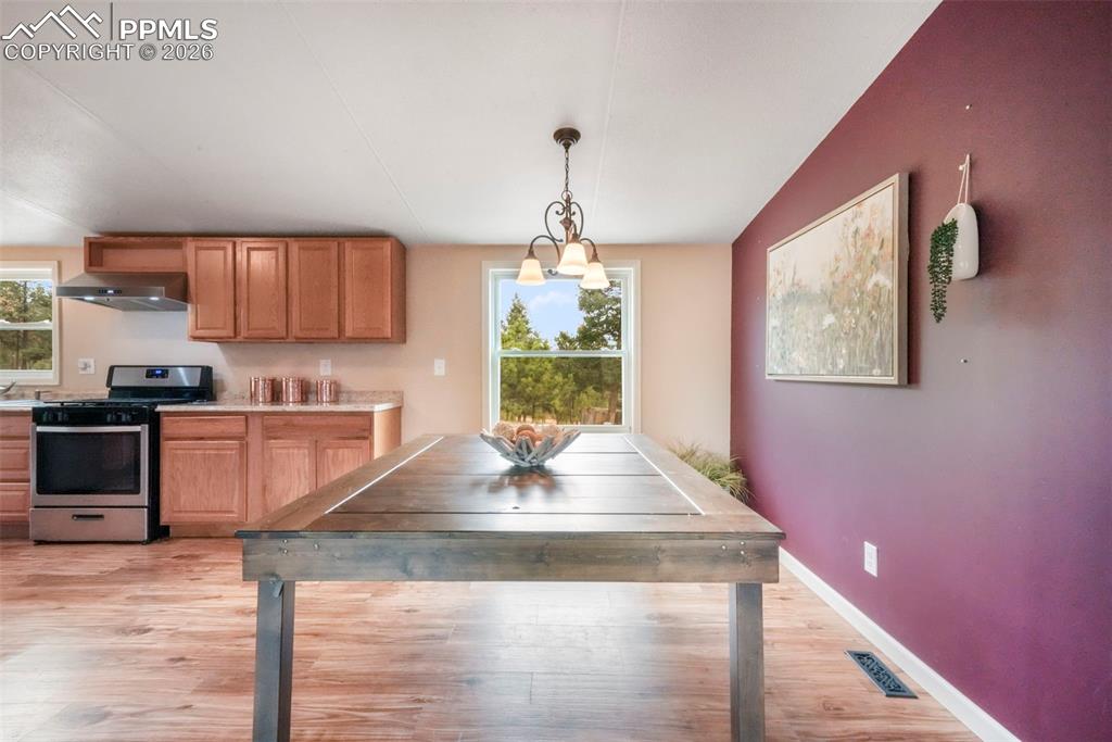 Image 13 of 50: Kitchen with stainless steel gas range oven, light wood finished floors, li