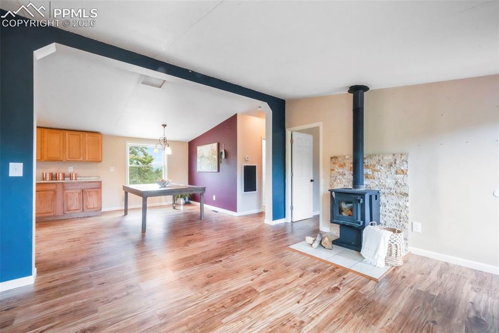 Image 17 of 50: Unfurnished living room with a wood stove and wood finished floors