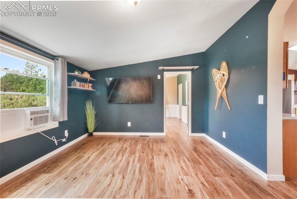 Image 19 of 50: Living room with a barn door, light wood-type flooring, and lofted ceiling