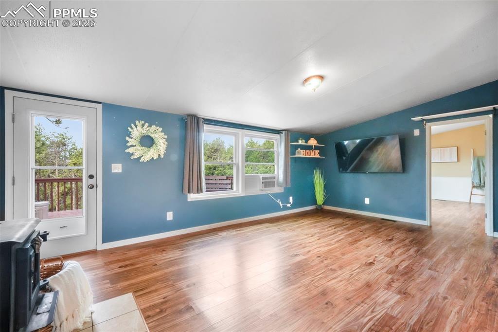 Image 21 of 50: Unfurnished living room featuring wood finished floors, a wood stove, and l