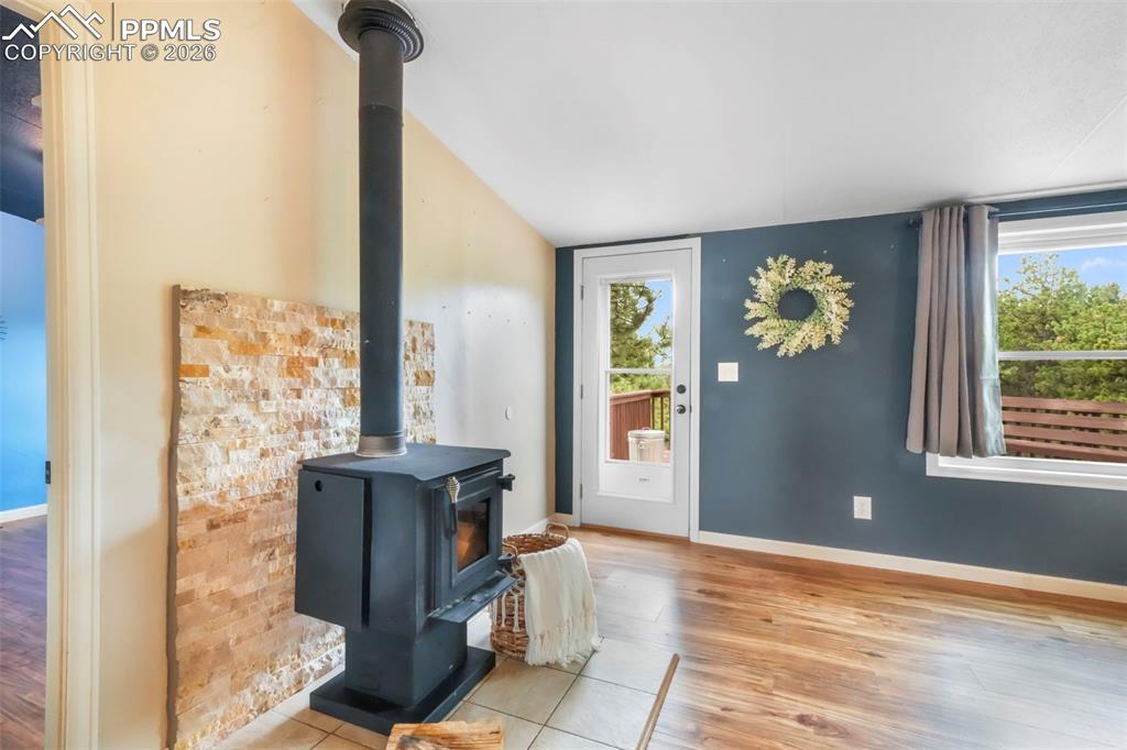 Image 22 of 50: Entrance foyer with a wood stove and light wood finished floors