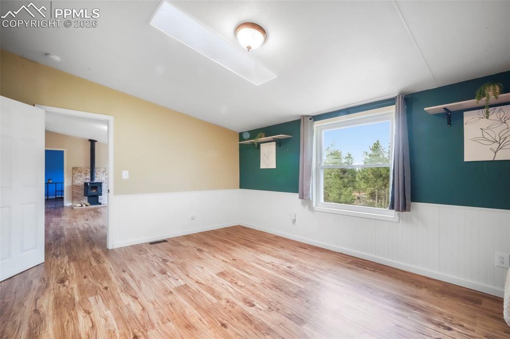 Image 25 of 50: Empty room with light wood-style floors and a wainscoted wall