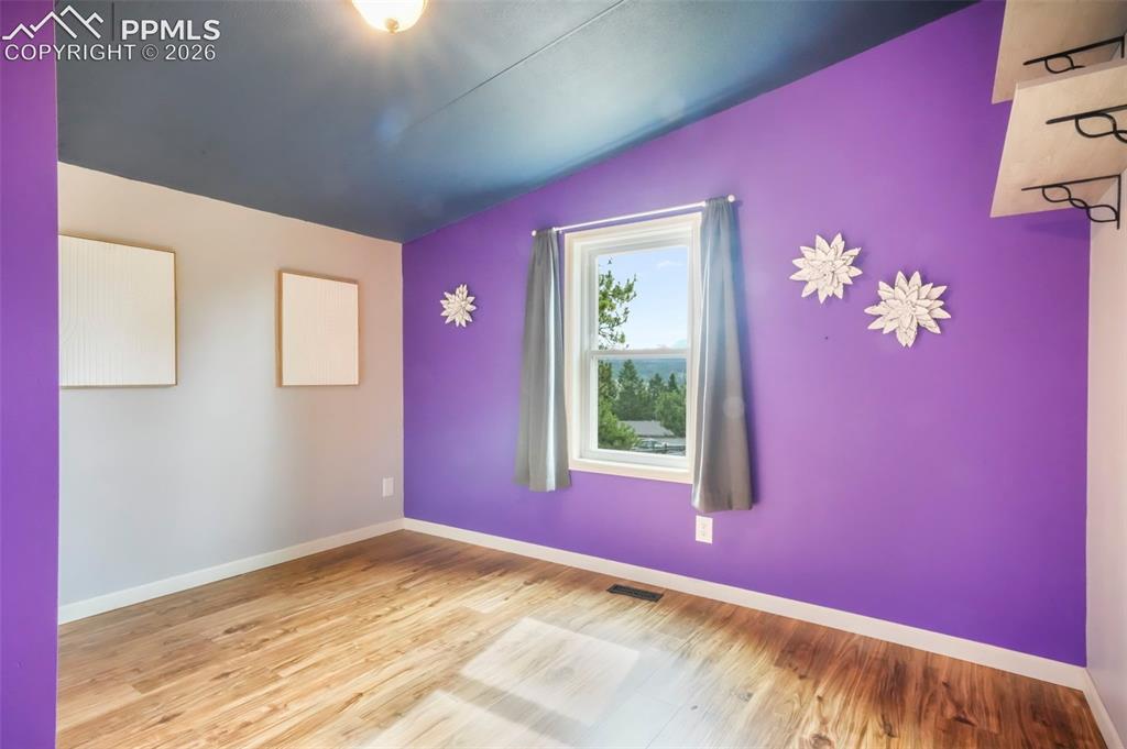 Image 34 of 50: Misc room with a textured ceiling, lofted ceiling, and light wood-type floo