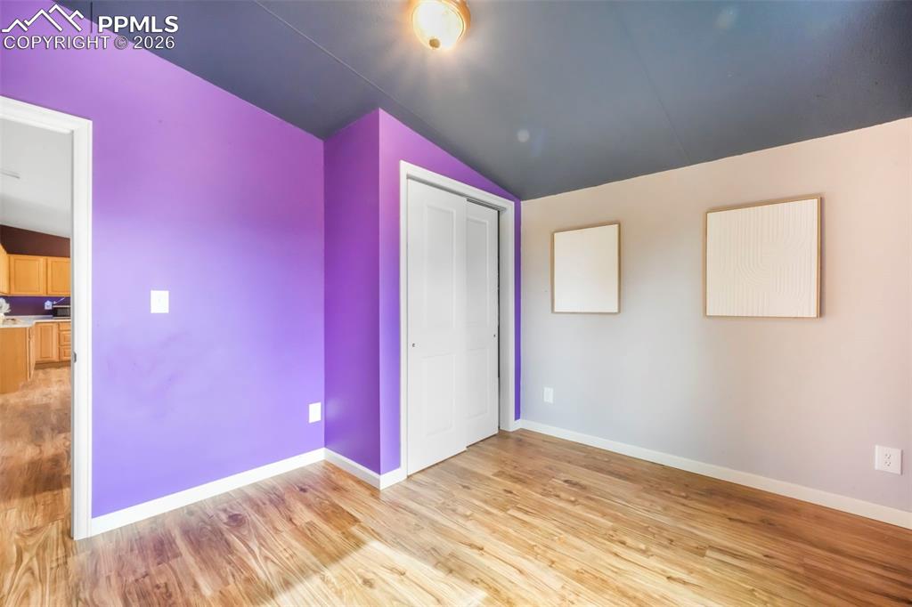 Image 35 of 50: Unfurnished bedroom with lofted ceiling, light wood-style flooring, and a c