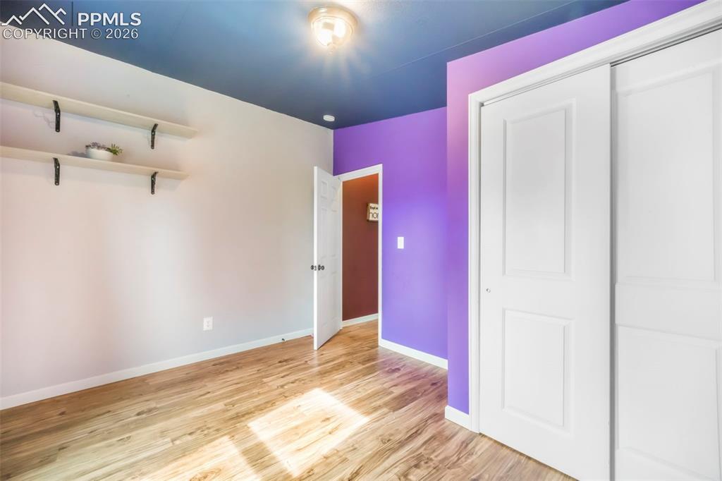 Image 36 of 50: Unfurnished bedroom with lofted ceiling, light wood-style flooring, and a c