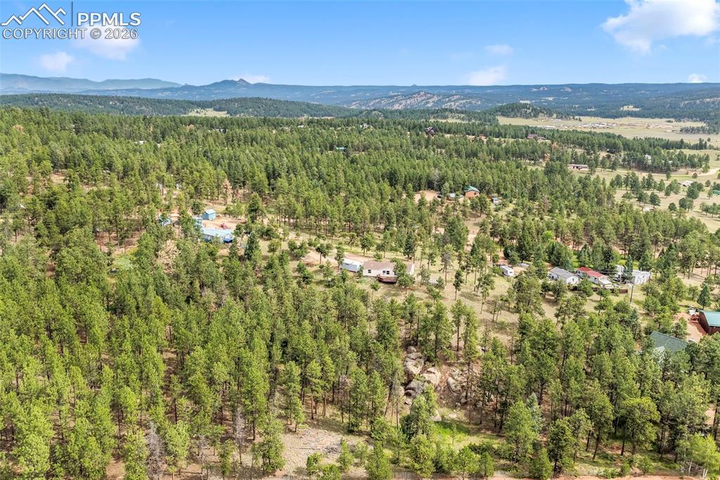Image 45 of 50: Drone / aerial view of a mountain backdrop and a heavily wooded area