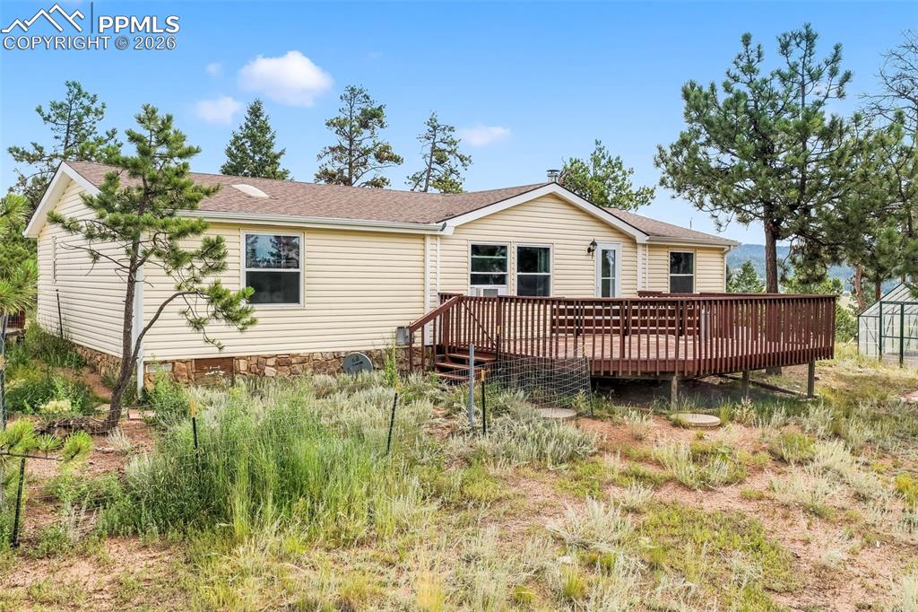 Image 49 of 50: Rear view of property featuring a wooden deck and roof with shingles