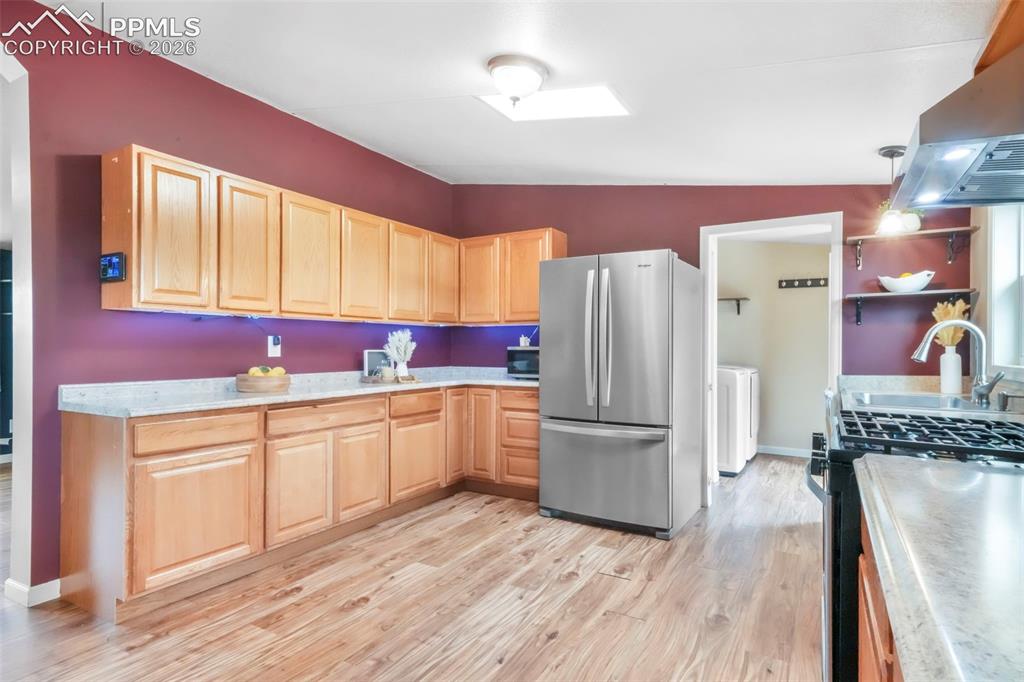 Image 7 of 50: Kitchen with open shelves, stainless steel appliances, a skylight, vaulted