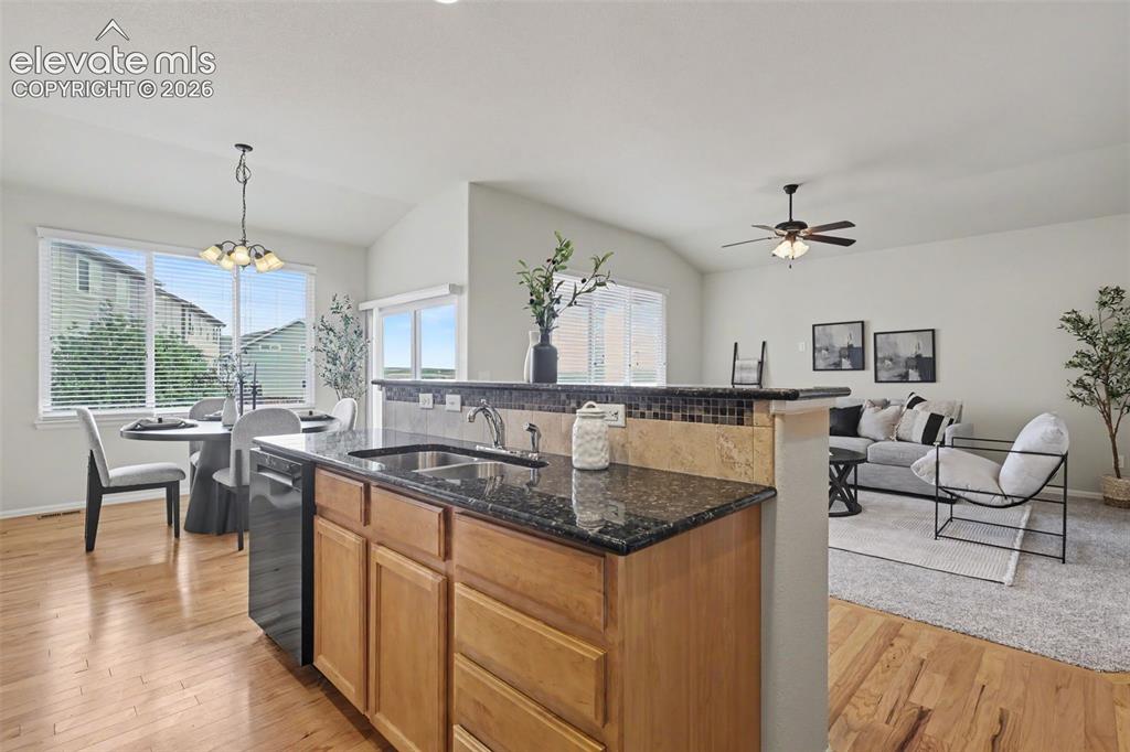 Image 13 of 39: Open-concept kitchen featuring granite countertops, wood cabinetry, a tiled