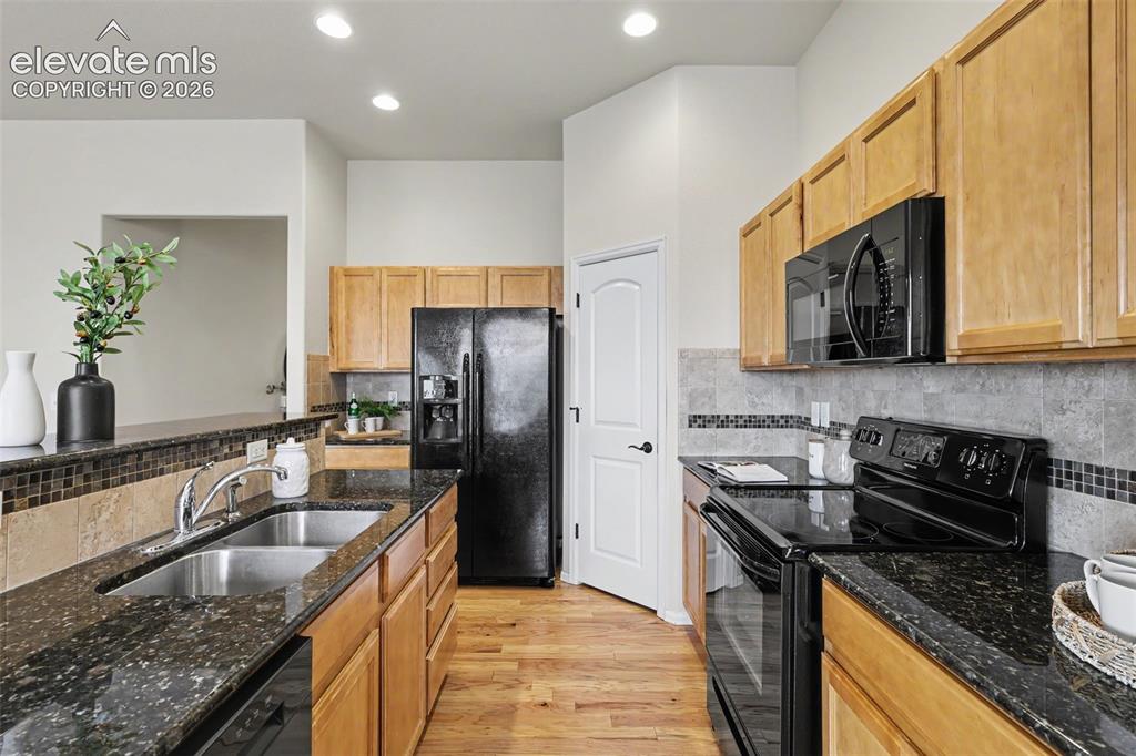 Image 15 of 39: Kitchen featuring wood-finish flooring, granite countertops, and light wood