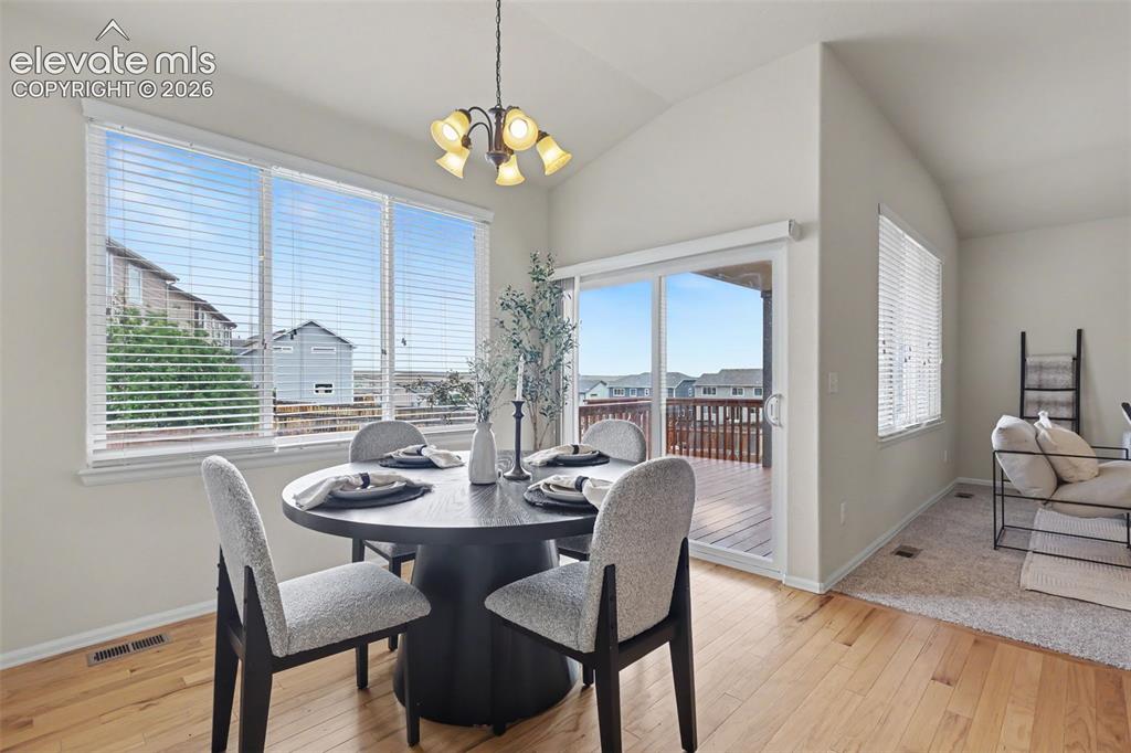 Image 17 of 39: Dining area featuring wood-finish flooring, vaulted ceilings, and a multi-p