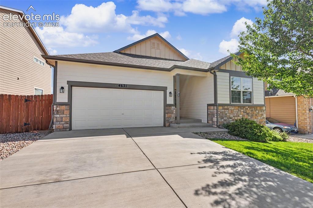 Image 2 of 39: Ranch-style residence featuring a prominent two-car garage, stone and sidin