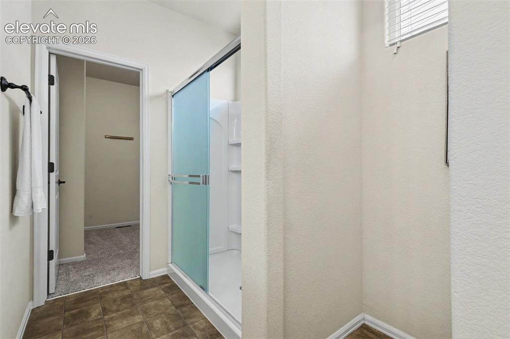 Image 23 of 39: Shower enclosure featuring frosted glass sliding doors and a built-in shelf