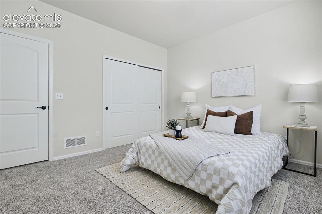 Image 26 of 39: Bedroom featuring light-colored walls, grey textured carpeting, white baseb