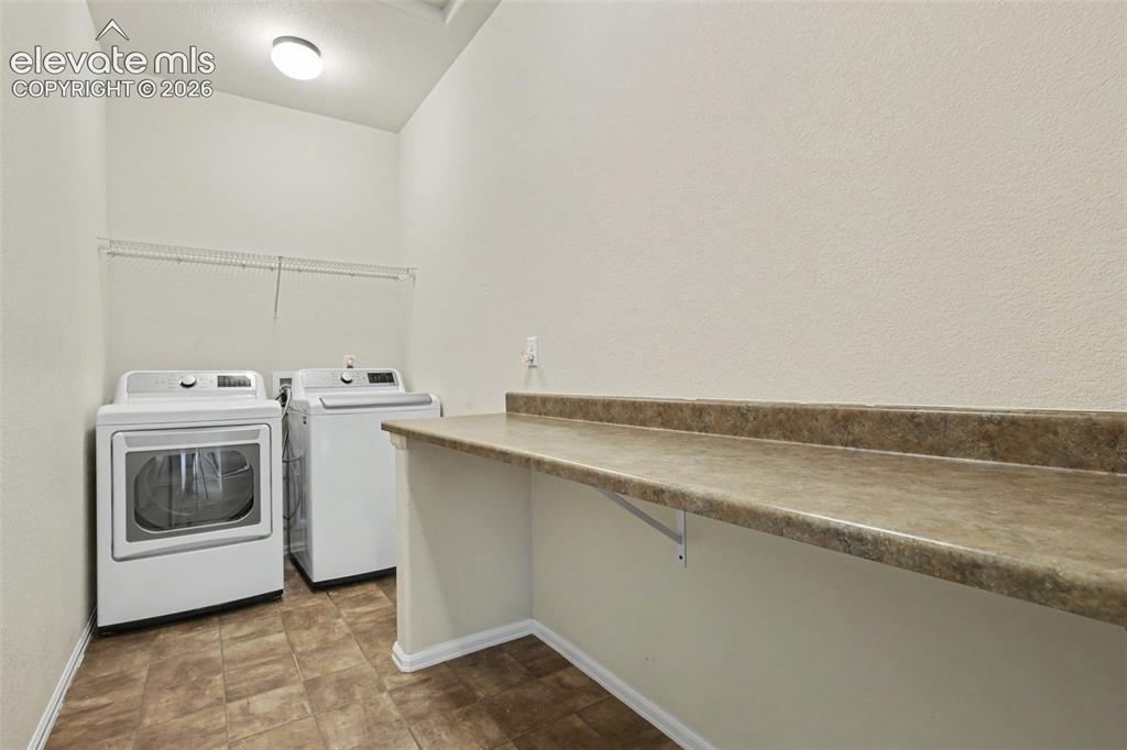 Image 31 of 39: Laundry room with patterned tile flooring, a wall-mounted wire shelf, and a