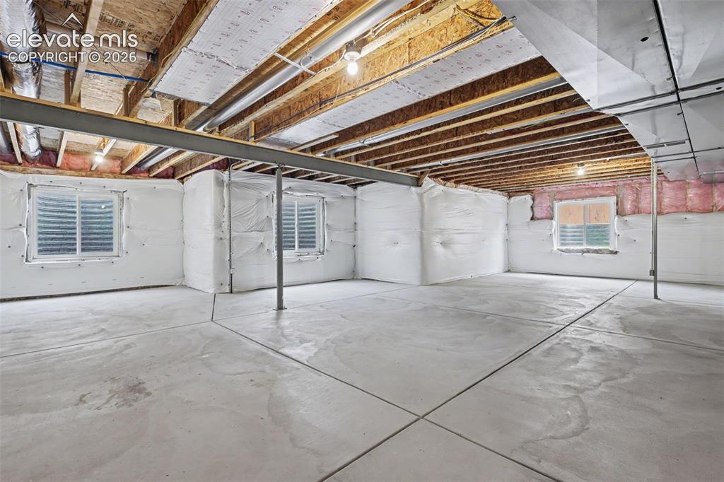 Image 32 of 39: Unfinished basement with concrete flooring, exposed wood ceiling joists, an