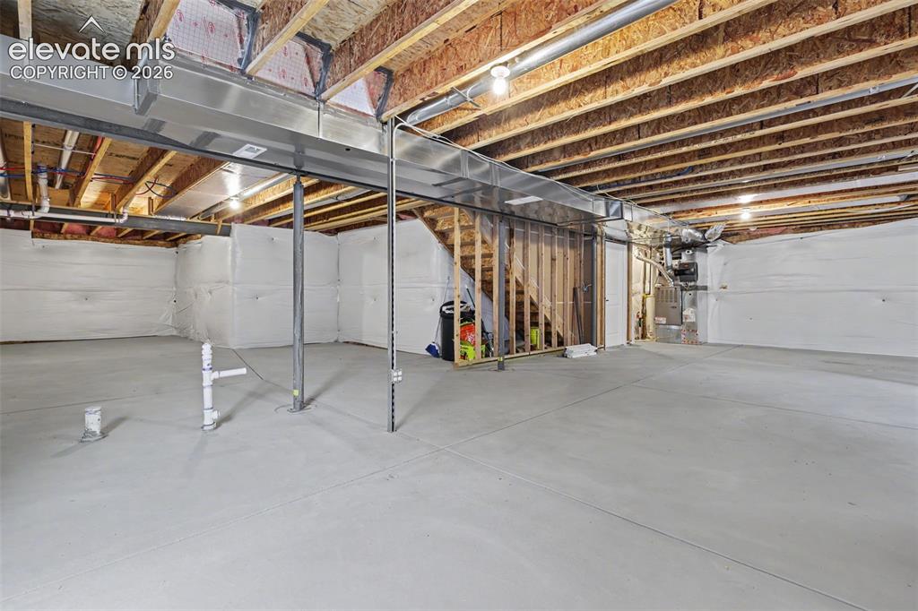 Image 34 of 39: Spacious unfinished basement featuring concrete flooring, exposed wooden jo