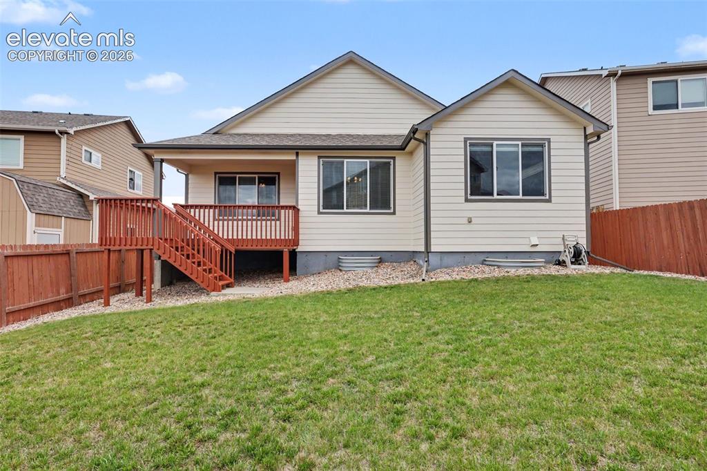 Image 37 of 39: Expansive backyard featuring a green lawn, wood fence, and a multi-level wo
