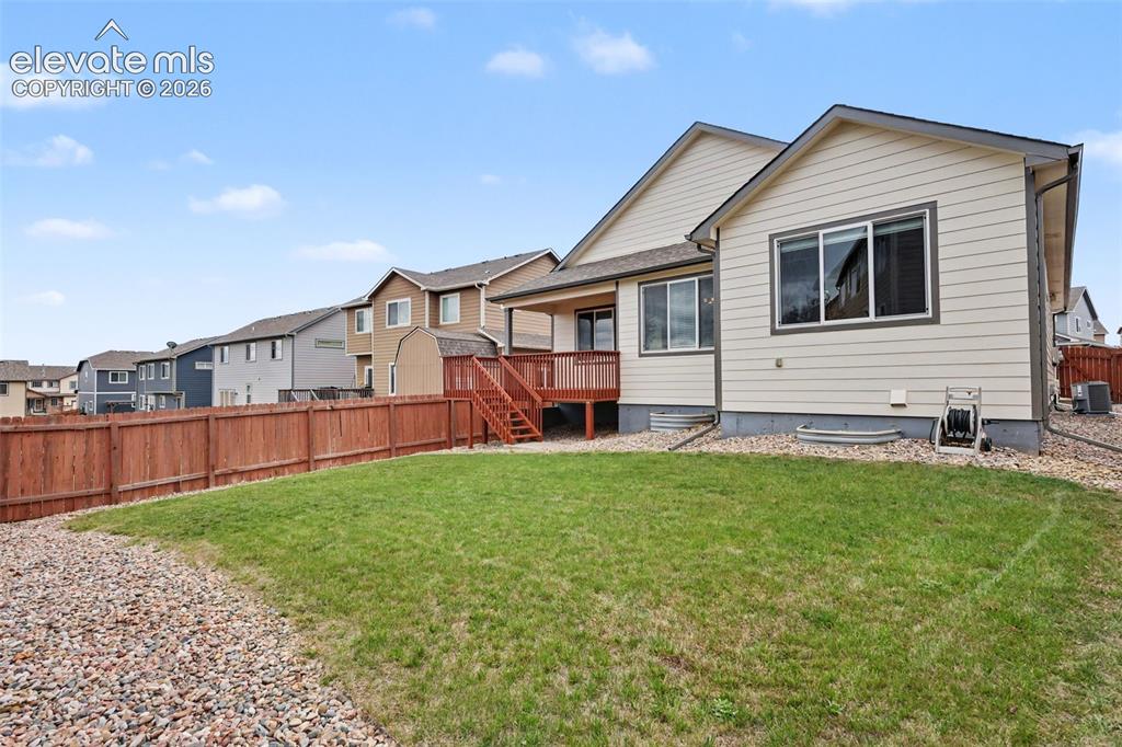 Image 38 of 39: Expansive rear yard featuring green lawn, a rock border, and a wood privacy