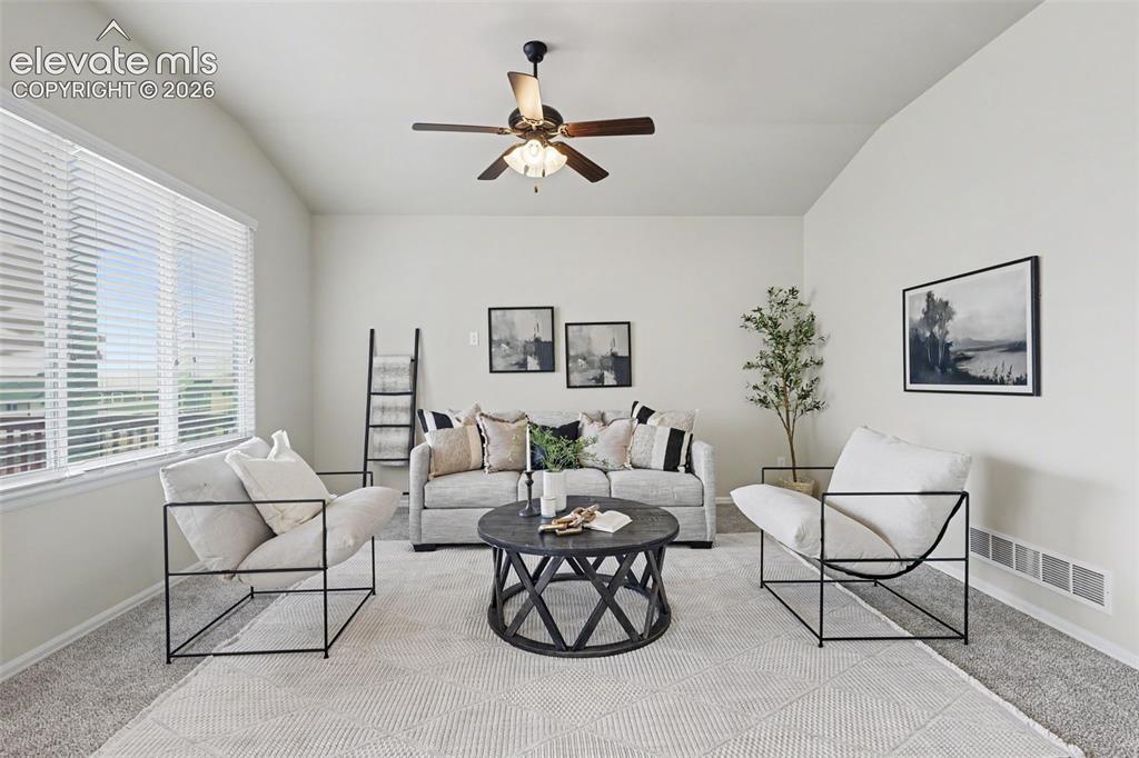 Image 6 of 39: Spacious living area featuring a vaulted ceiling and ample natural light fr
