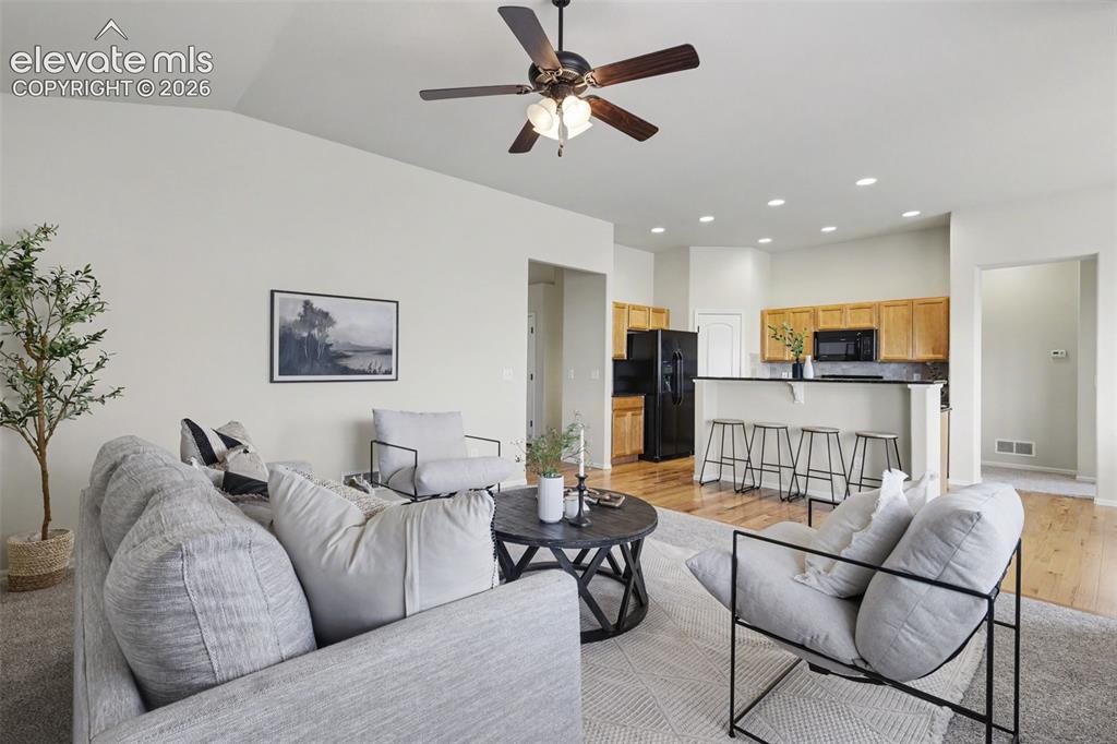 Image 8 of 39: Spacious living area featuring vaulted ceilings, a ceiling fan with integra
