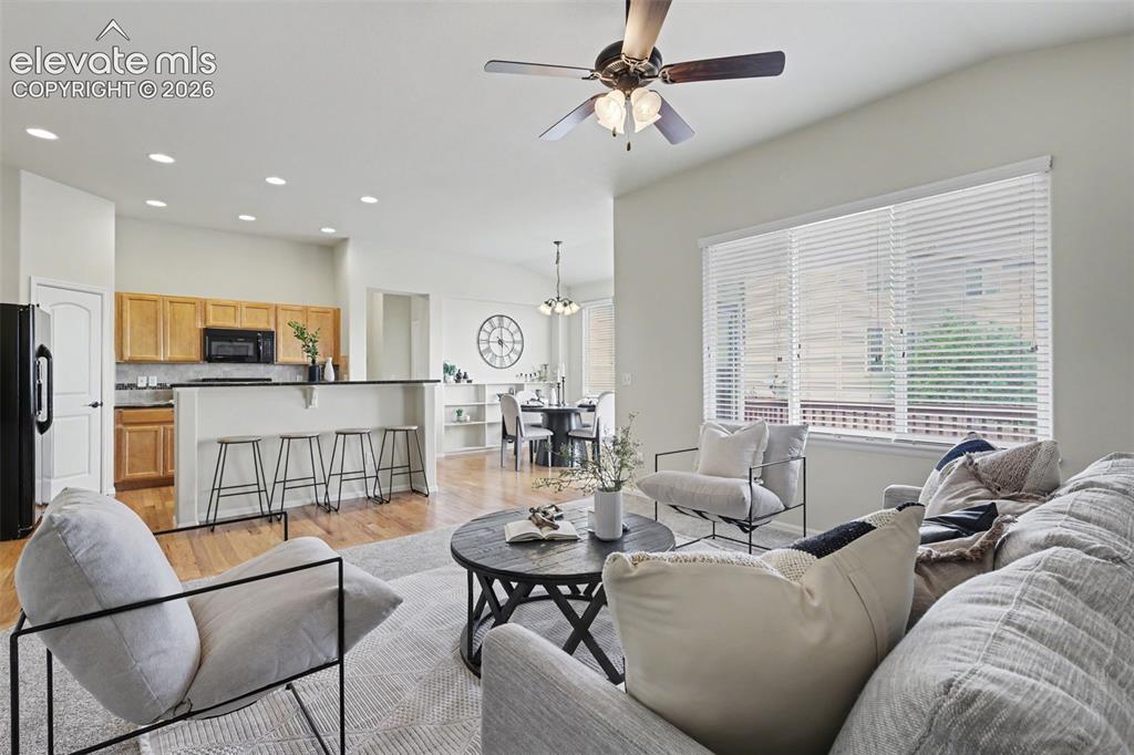 Image 9 of 39: Open-concept living area featuring a vaulted ceiling with a ceiling fan, re