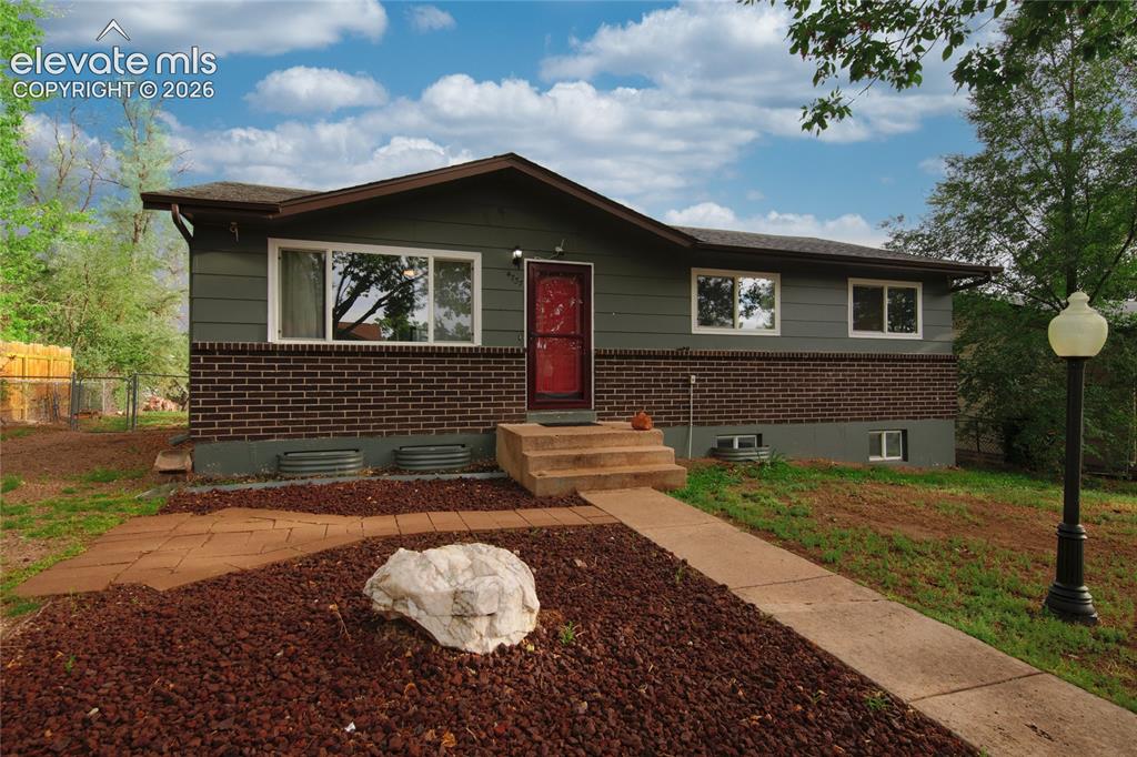 Image 1 of 34: Welcoming brick and siding exterior featuring a red entry door, multi-pane