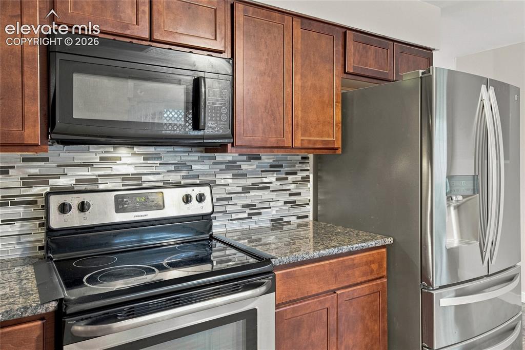 Image 10 of 34: Modern kitchen featuring rich wood cabinetry, stainless steel appliances in
