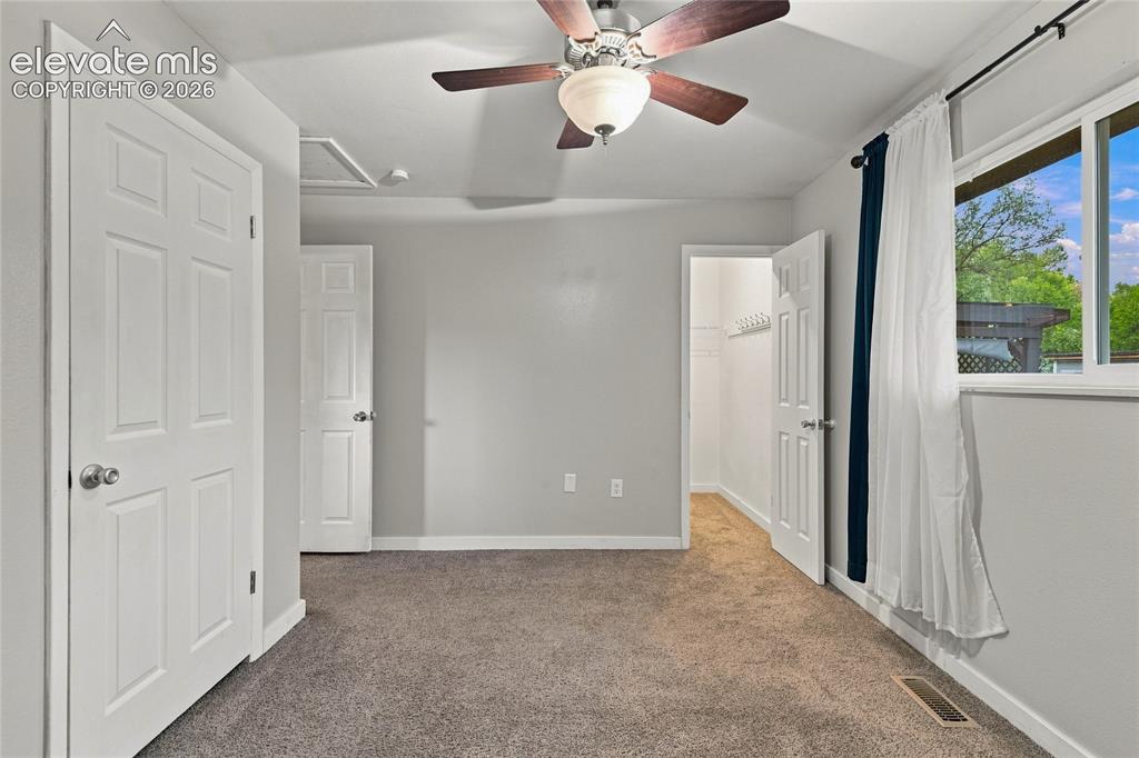 Image 15 of 34: Spacious primary bedroom featuring walk-in closet, carpet flooring, a ceili