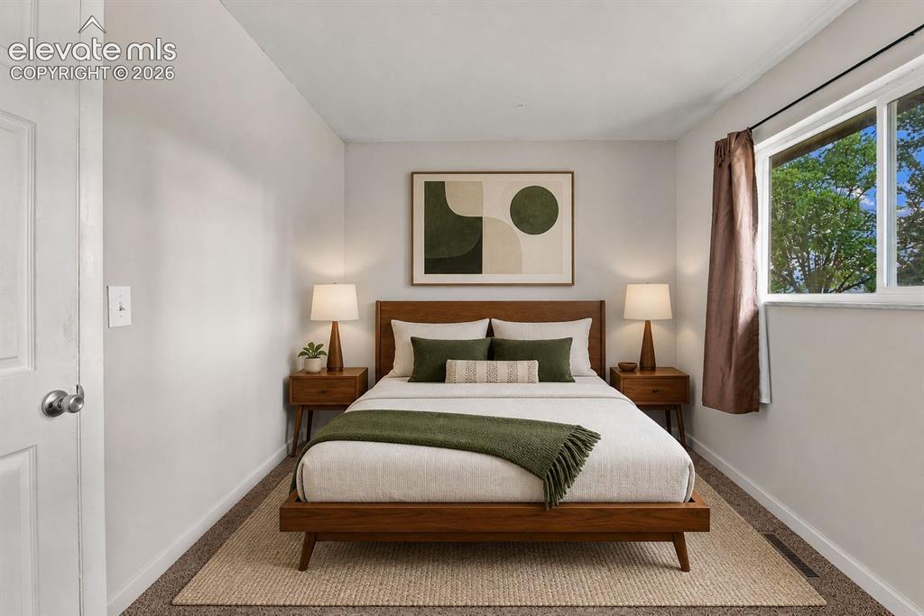 Image 17 of 34: Main level bedroom with large window, carpet and closet space
